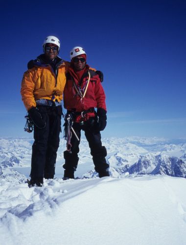 Andy cave standing on top of a mountain, smiling with a fellow explorer