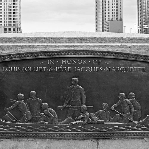 These oblong, shallowly carved tablets, mounted to the inner parapet walls of DuSable Bridge show in figures of French explorers and their American Indian guides rowing and disembarking from their canoes. In both tablets, the figures move as if in concert, in front of an ideal space with no indication of place, but rather against a blank background. 