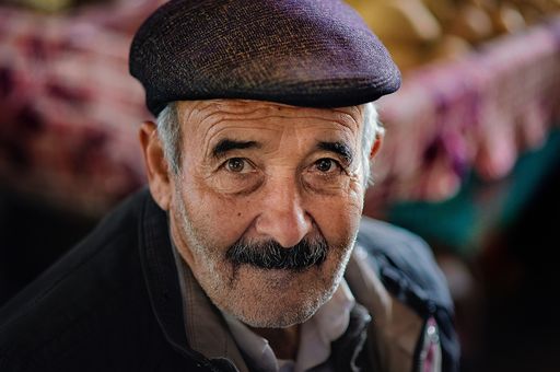 Photo of an older man with dementia, he has grey hair, moustache and hat and is looking at the camera