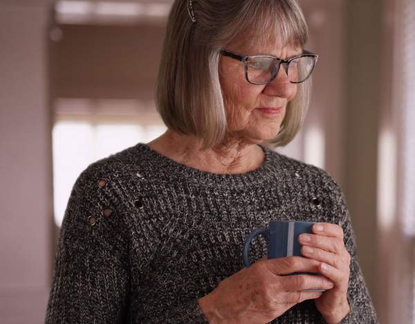 Senior woman drinking tea while looking out the window