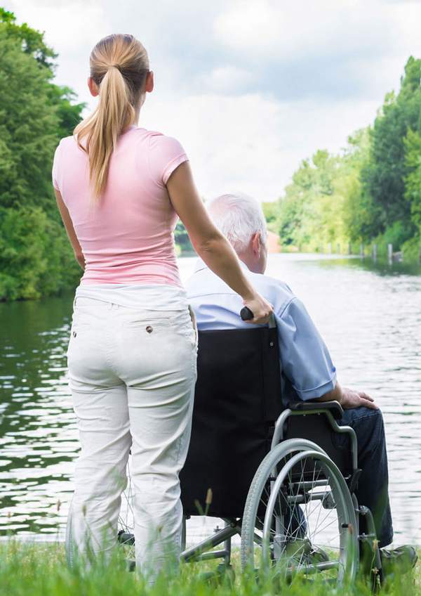 Senior woman and carer sitting by the lake