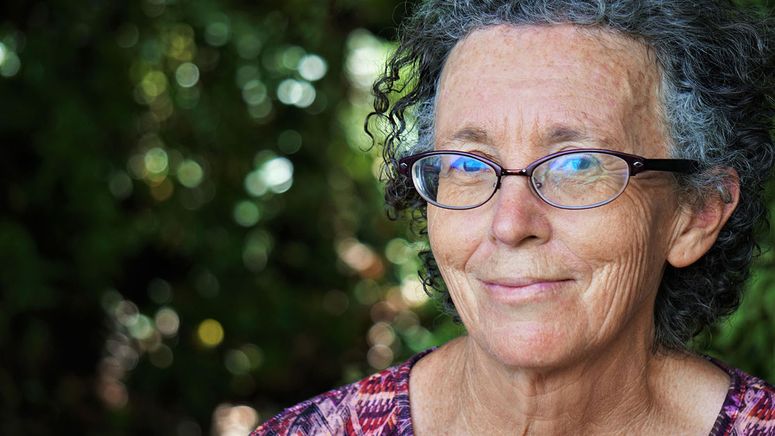 Dementia and respite- portait photo of a lady with curly grey hair and glasses smiling at the camera