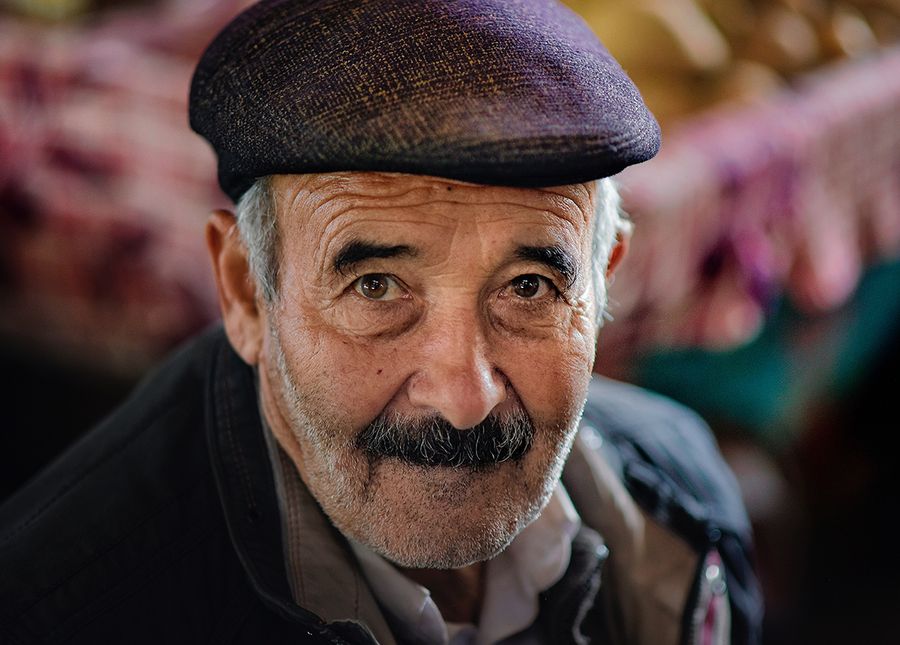 Photo of an older man, with dementia in respite, with hat, grey hair and moutache looking at the camera