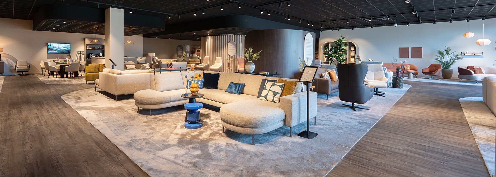 A modern furniture showroom with stylish sofas, colorful cushions, and decorative items on display, illuminated by overhead lighting.