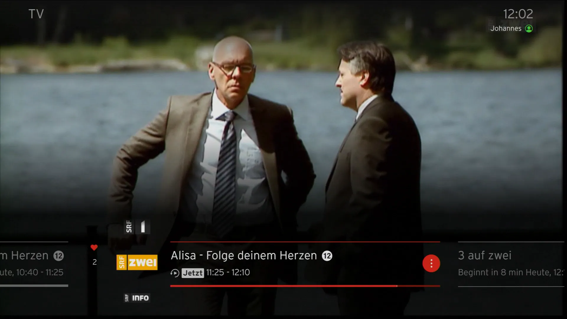 Vista della trasmissione in diretta nell'app TV con il pulsante di pausa, il pulsante OK e l'opzione di riavvolgimento.