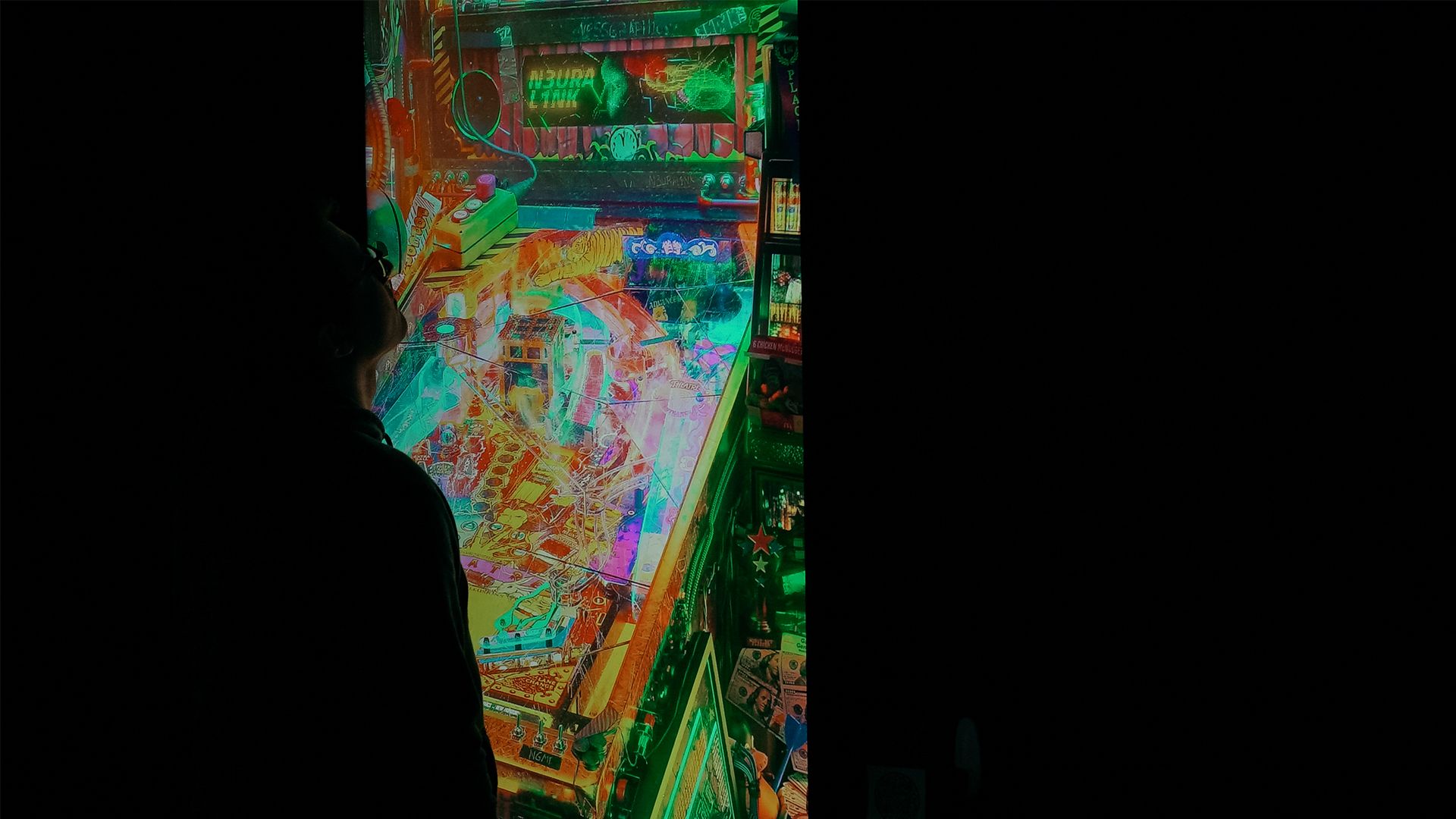 Alex Ness in a dark room looking at a colourful digital artwork