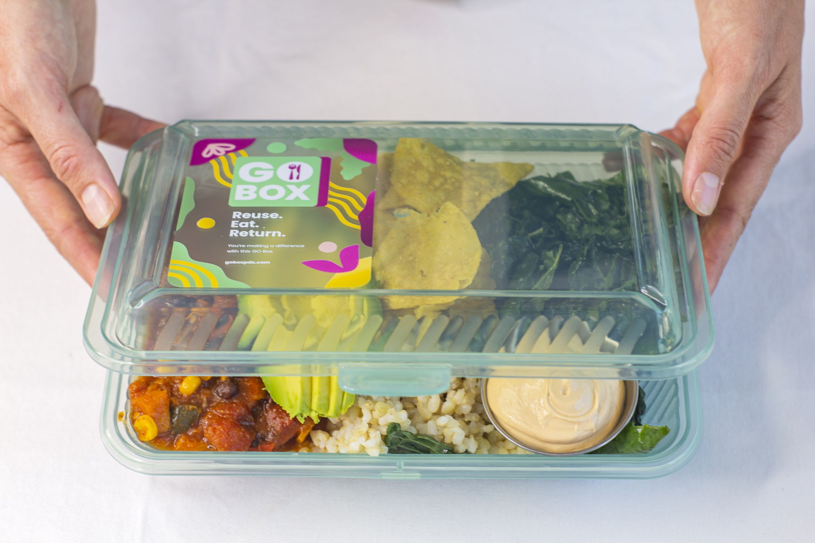 Hands holding Go Box reusable box in office catering food delivery