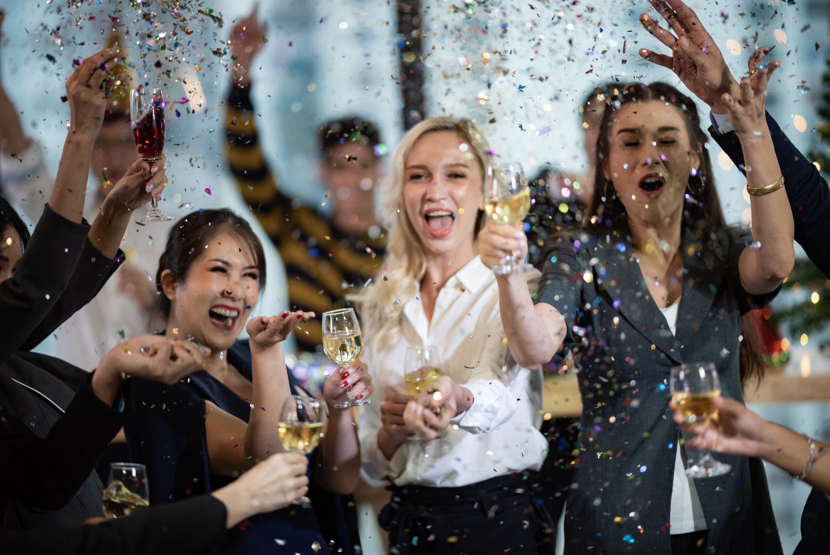Employees having fun at a company holiday party throwing confetti drinking champagne