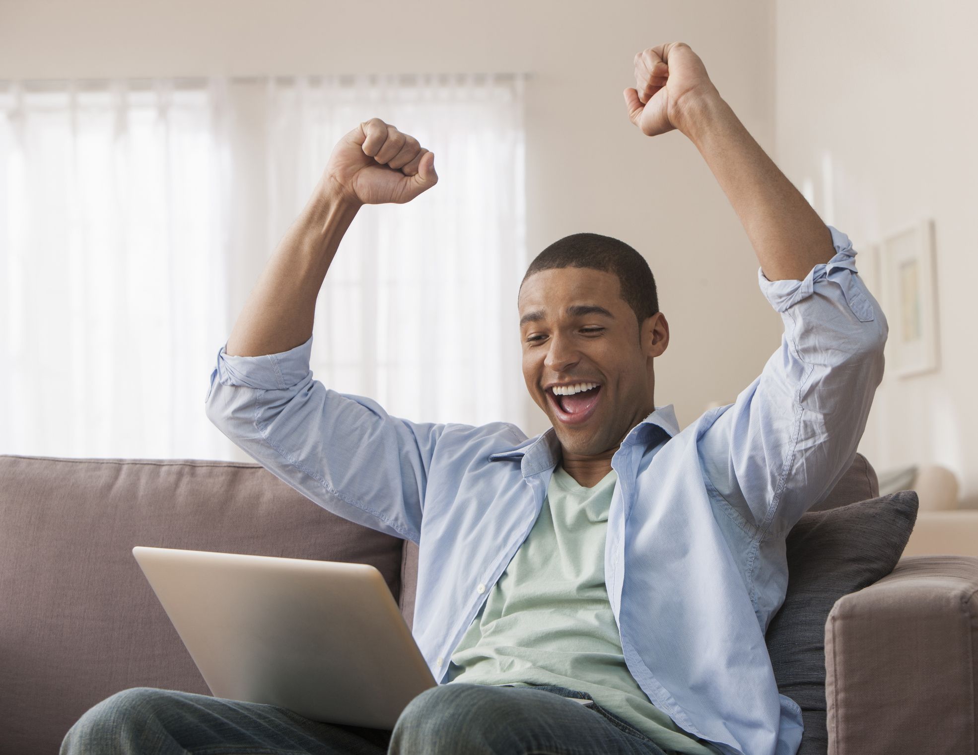 man excited sitting at computer winning