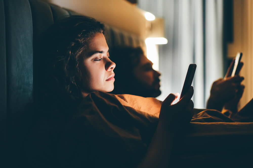 Digitální závislost - pár v posteli na mobilech