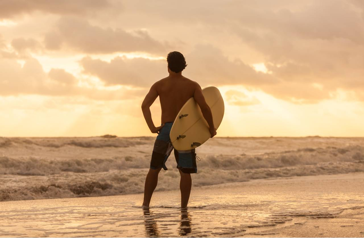 Surfař se dívá na západ slunce