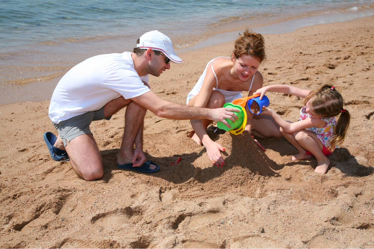 Rodina dělá bábovky na pláži