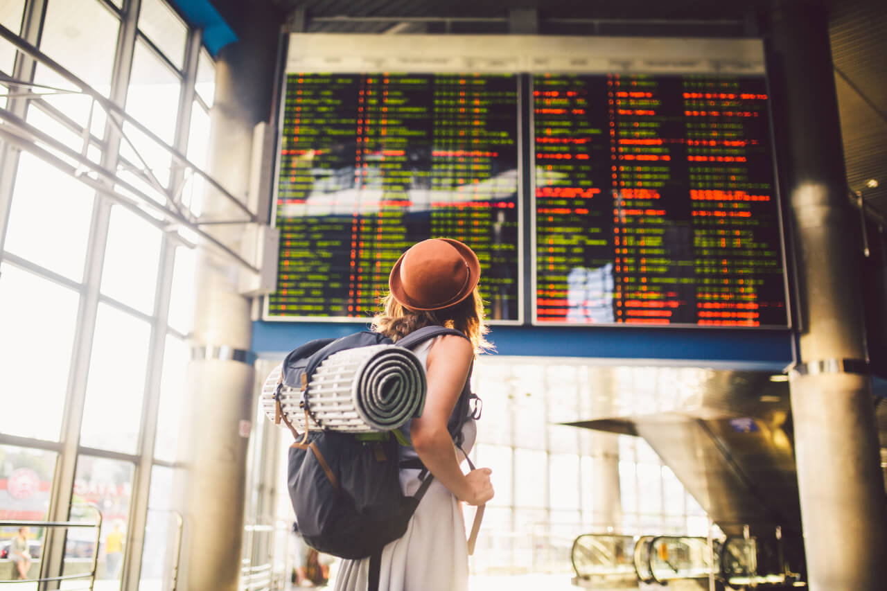 Žena stojí před odletovou tabulí na letišti