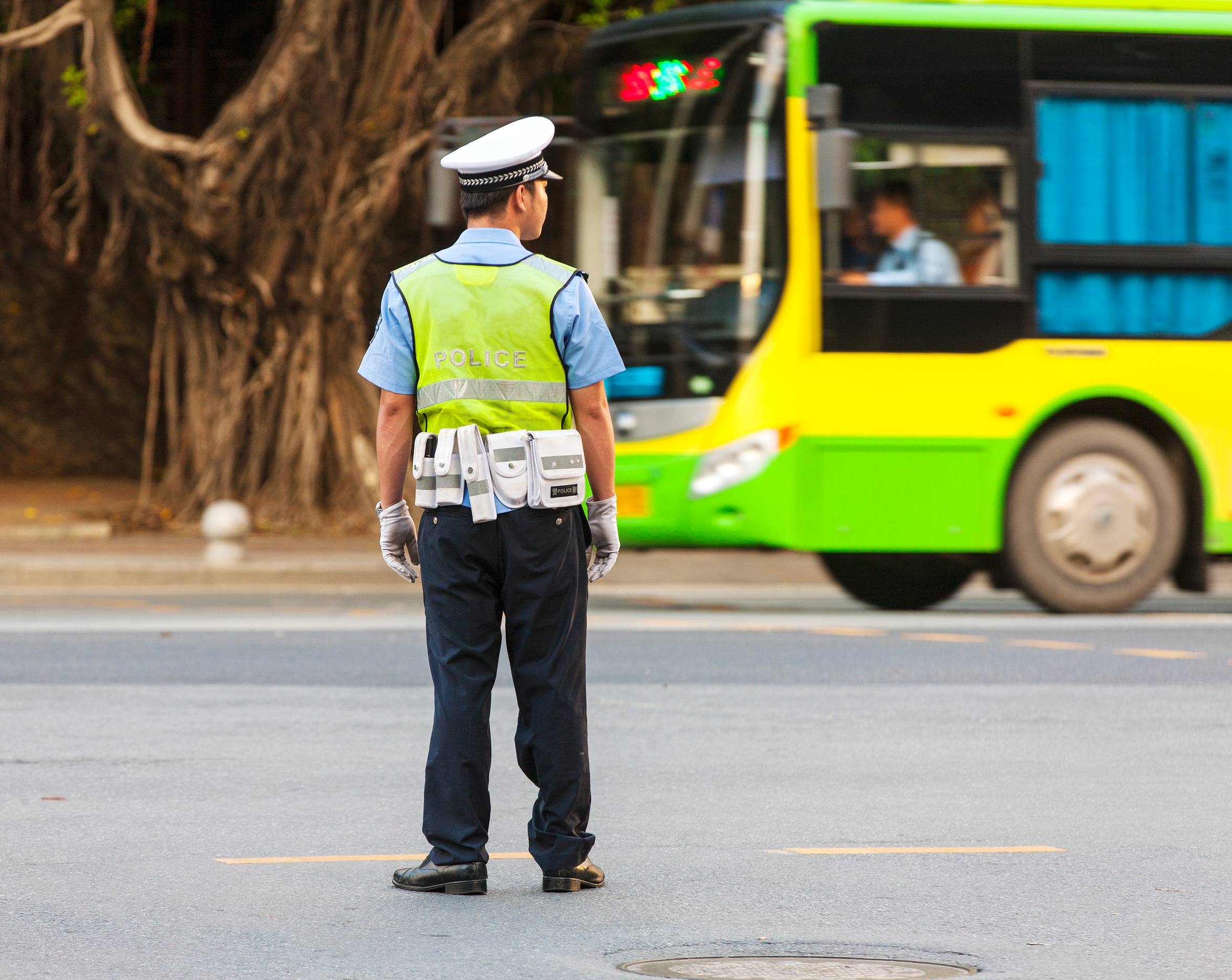 Policista na silnici a projíždějící autobus