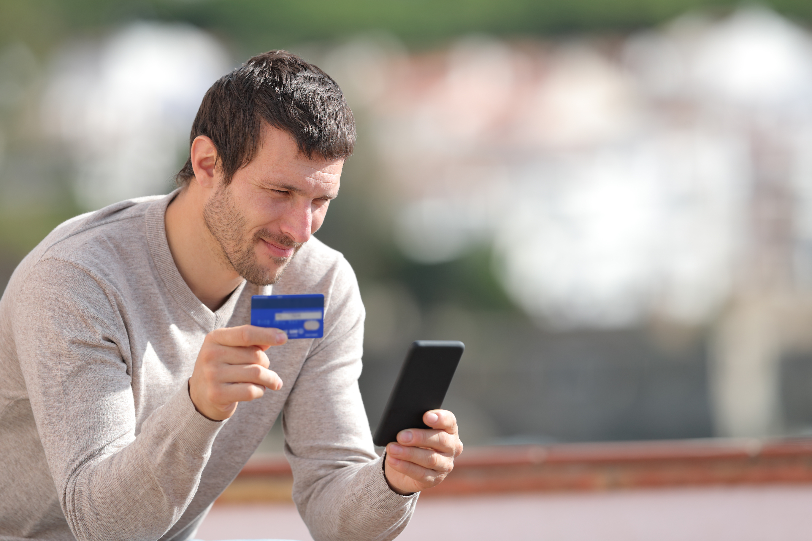 Muž držící mobil a kreditku