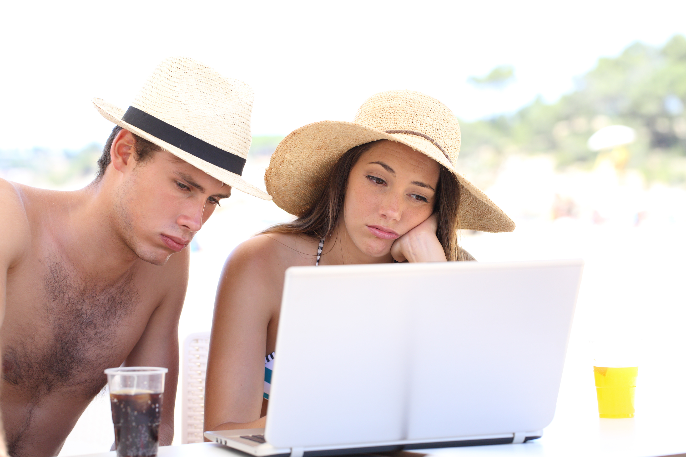 Znuděný muž a žena se dívají na dovolené do počítače