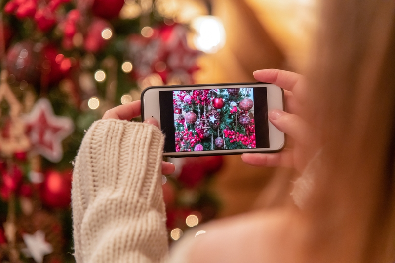 Žena fotí telefonem vánoční stromek