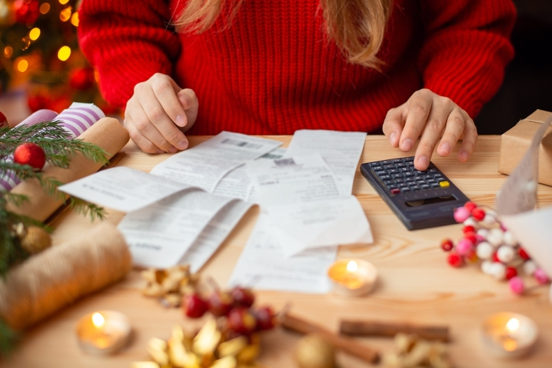 Účty za vánoční dárky - žena počítá na kalkulačce