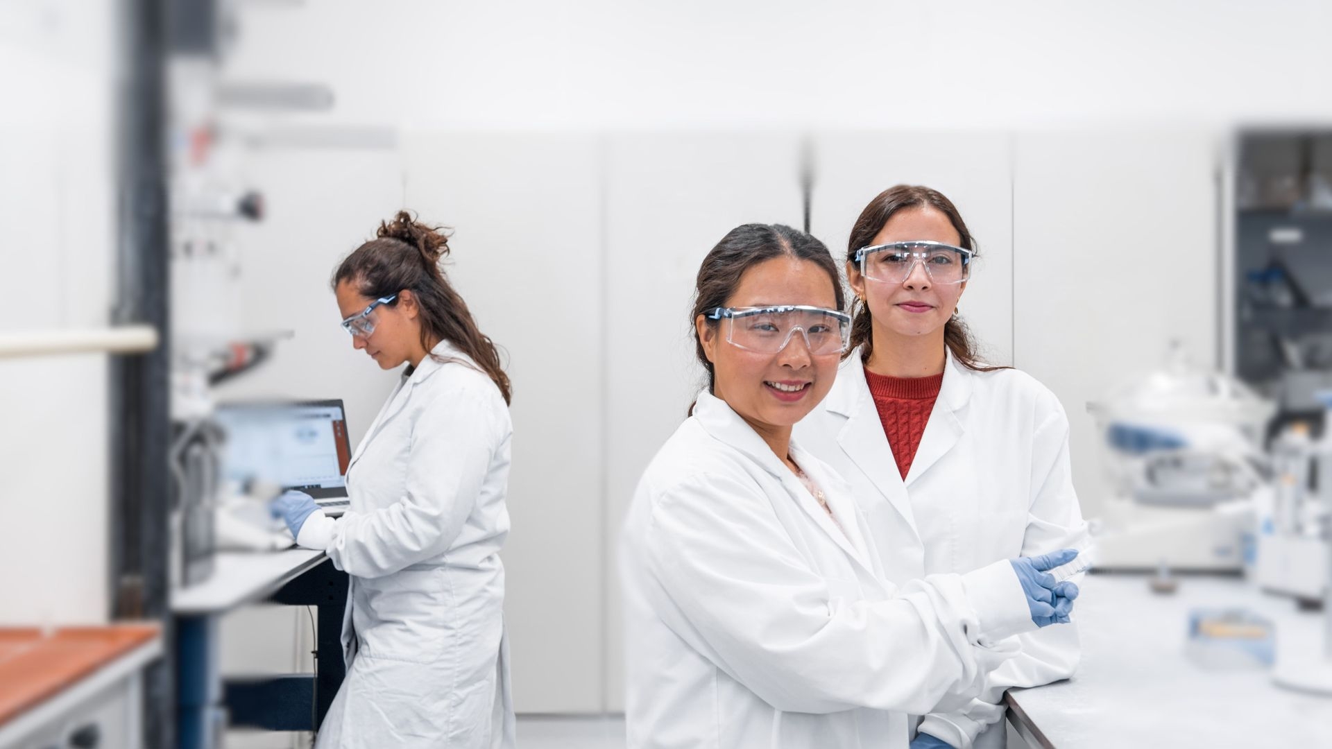 Drie medewerkers van CAM Bioceramics in witte labjassen en veiligheidsbrillen in het laboratorium in Leiden