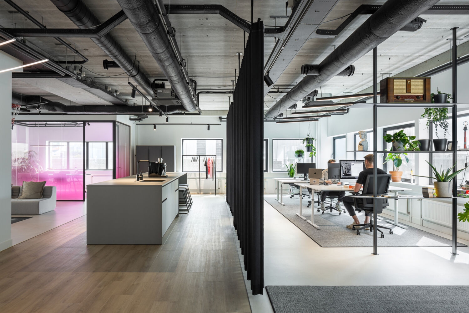 Overzicht van het Stuurmen-kantoor met keuken, werkplekken, planten en industriële details