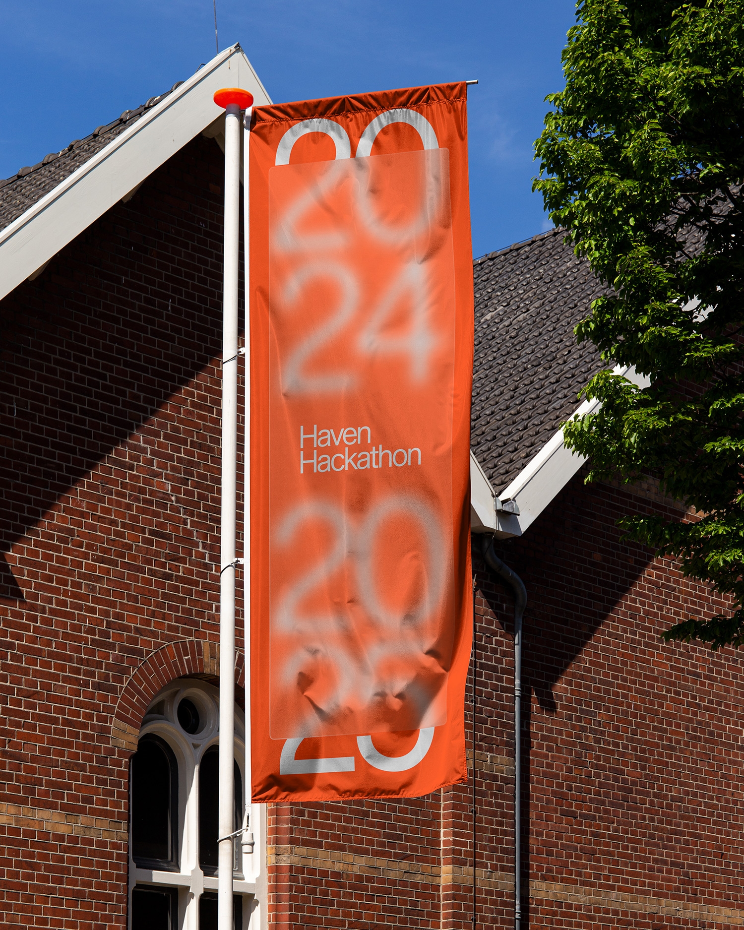 Oranje banner voor de Haven Hackathon 2025 aan de gevel van een bakstenen gebouw