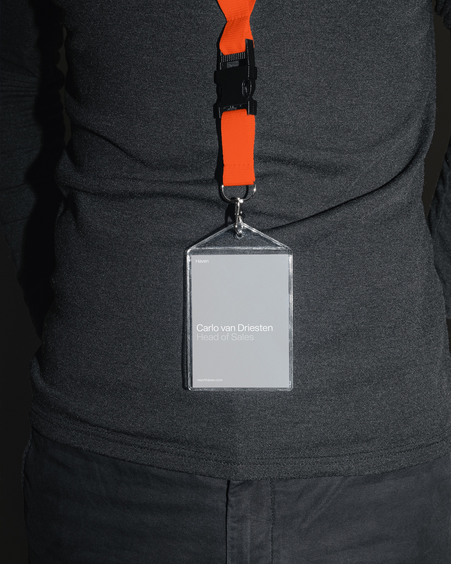 Naamkaartje aan een oranje keycord gedragen over zwarte kleding