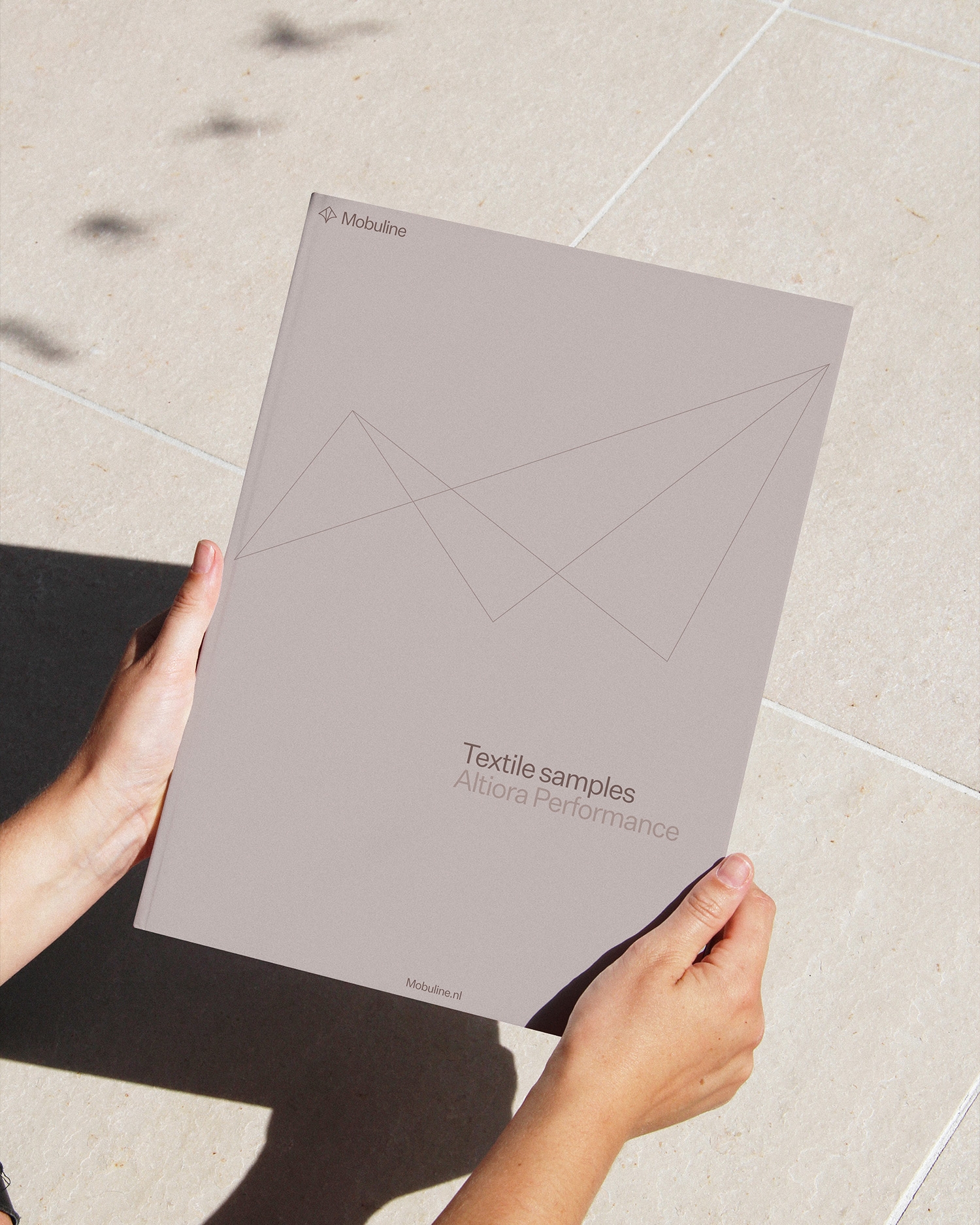 Persoon houdt een Mobuline-map met textielstalen en productspecificaties vast.
