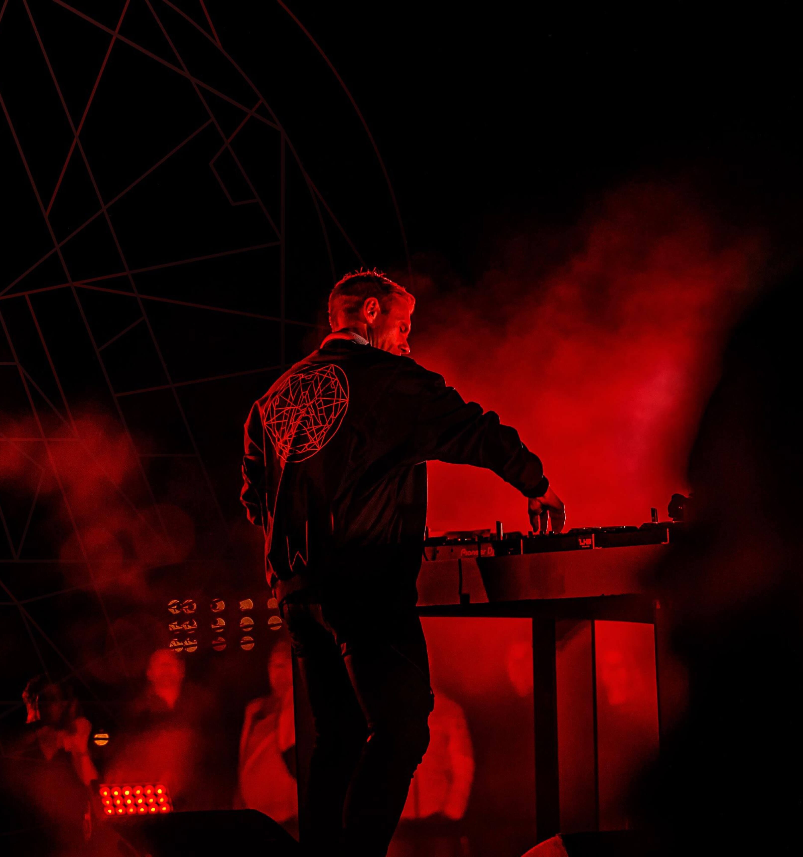 DJ op een podium van TWOFIFTYK, in rood licht binnen een geometrische lichtkoepel