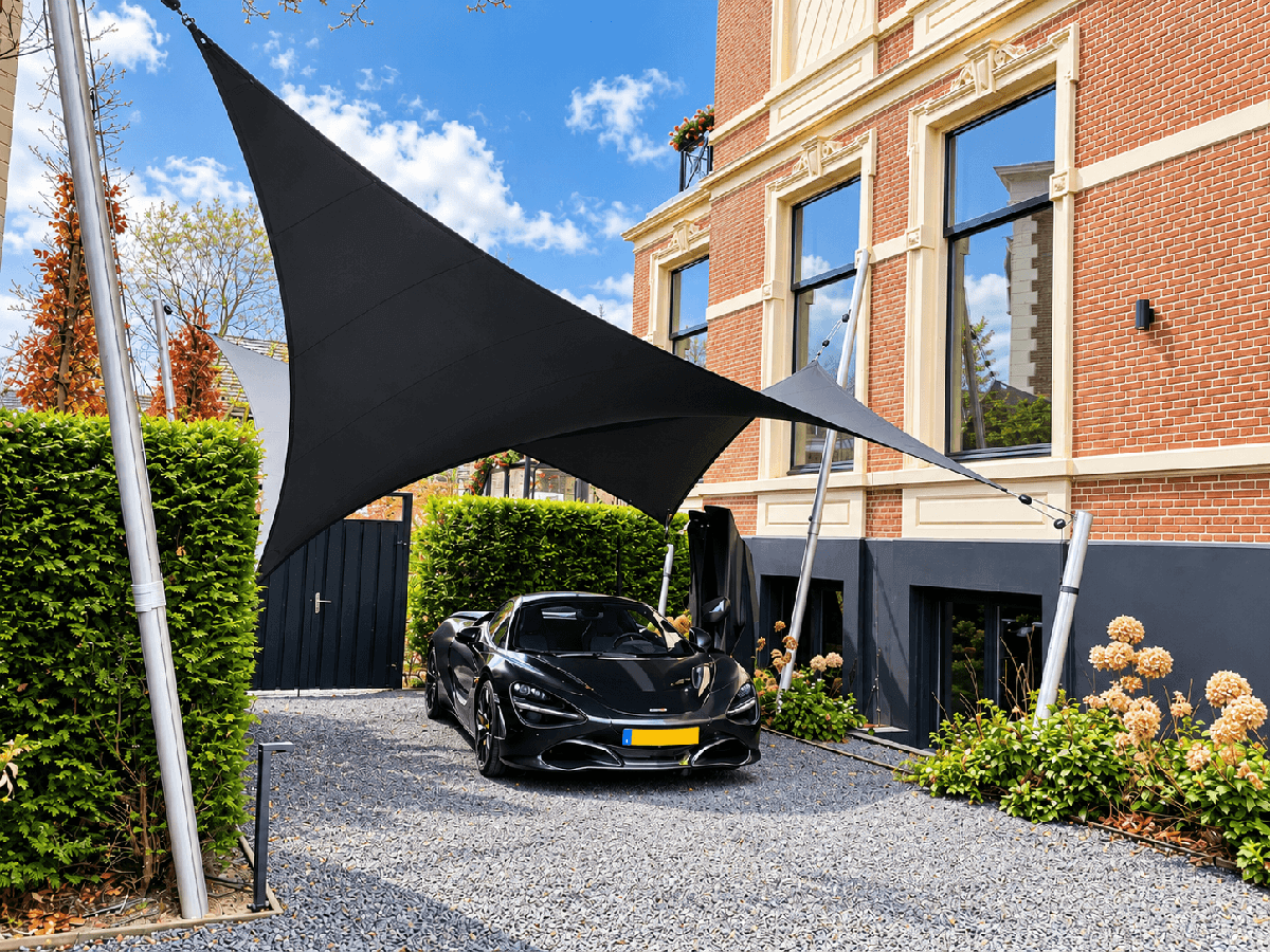 Vrijstaande Mobuline carport met zwart schaduwdoek op maat boven een auto bij een karakteristieke woning.