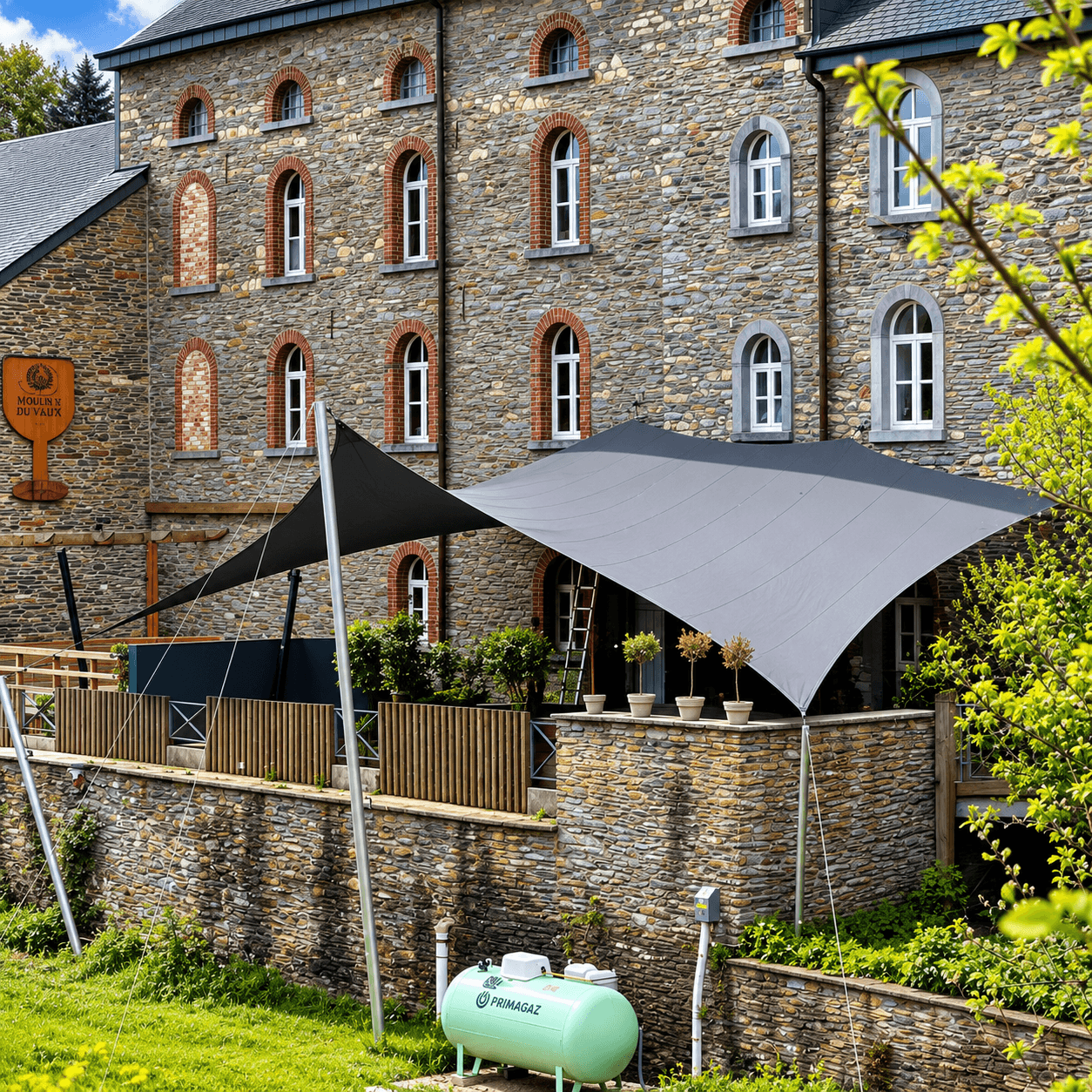 Maatwerk textiele overkapping boven een terras bij een karakteristiek historisch gebouw.