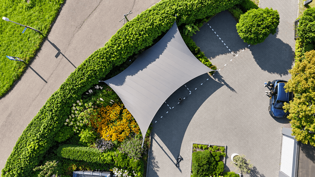 Maatwerk carport van textiel van Mobuline boven een oprit, gezien vanuit de lucht.
