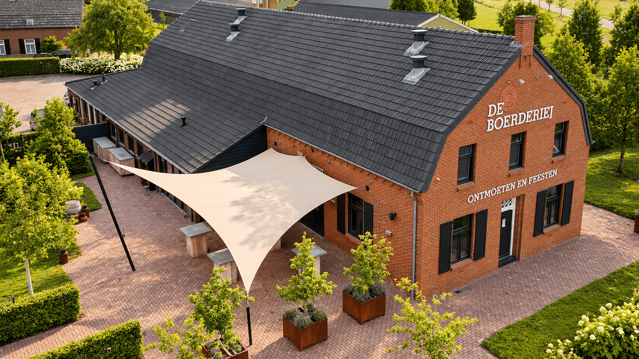 Maatwerk textiele overkapping boven het terras van De Boerderij, gezien vanuit de lucht.
