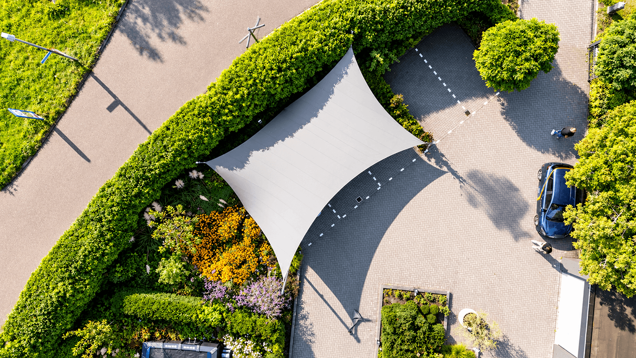Luchtfoto van een witte design carport van textiel, op maat gespannen boven een parkeerplaats.