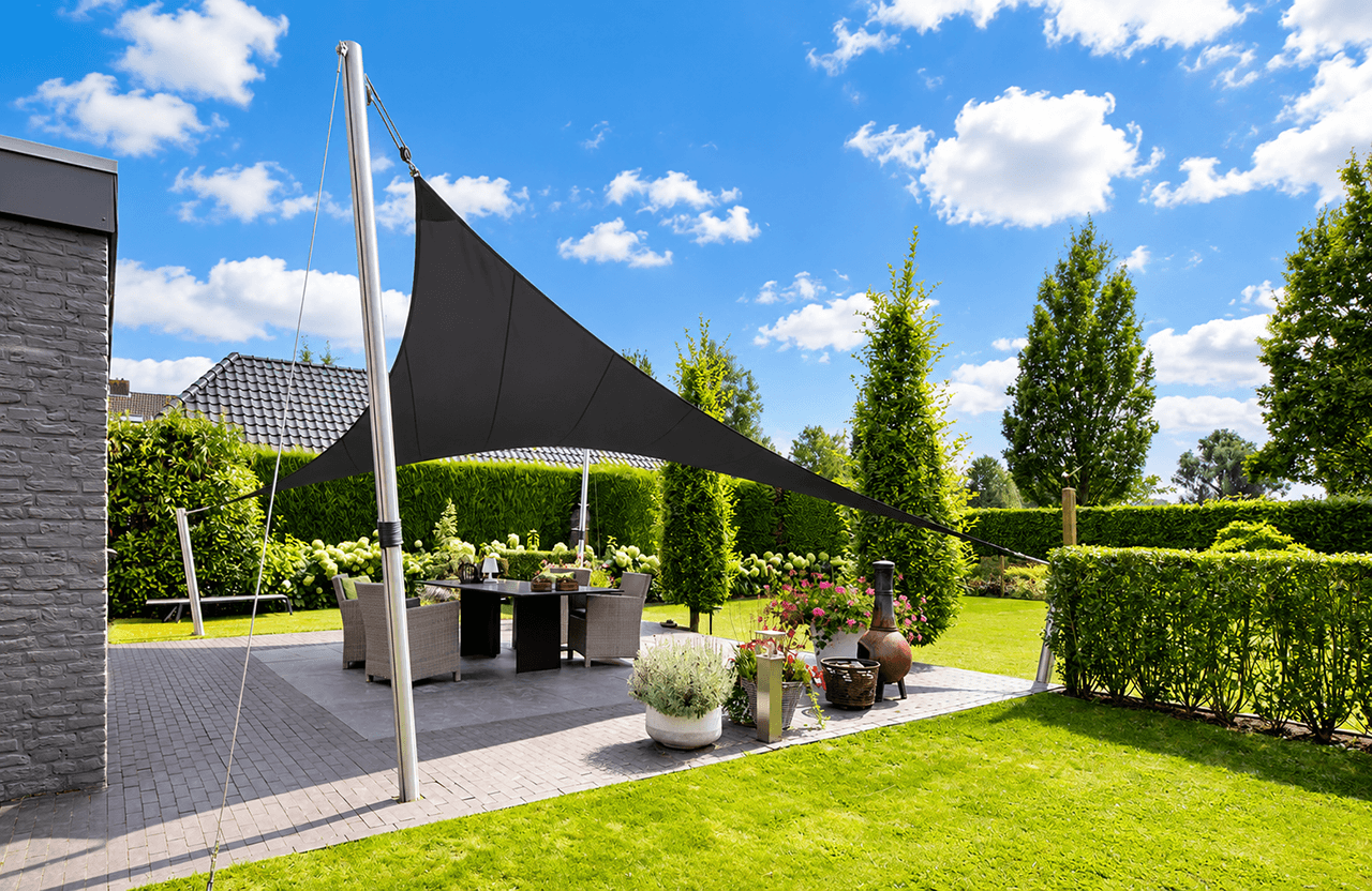 Maatwerk zonnedoek van Mobuline boven een terras in een groene tuin voor comfortabele schaduw.