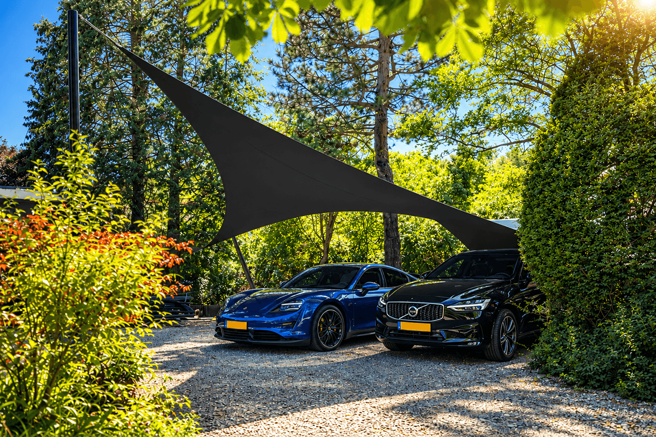 Architectonische design carport van Mobuline met zwarte textieloverkapping op maat voor twee auto’s bij een groene villa.
