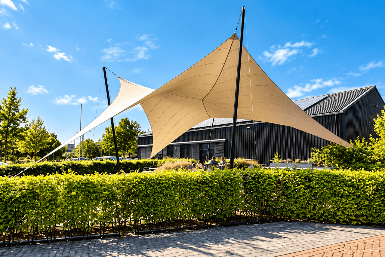 Grote maatwerk membraanoverkapping boven een ruim horecaterras, gedragen door meerdere masten.