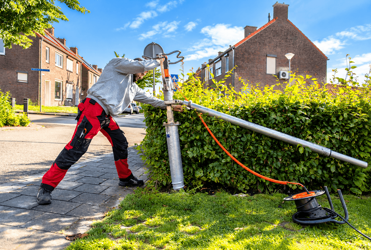 Monteur plaatst een funderingspaal voor de verankering van een maatwerk membraanoverkapping.