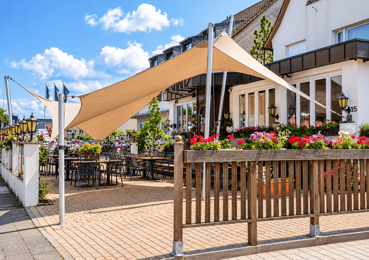 Luxe design schaduwdoek boven het terras van een horecagelegenheid met ruime zitplaatsen.