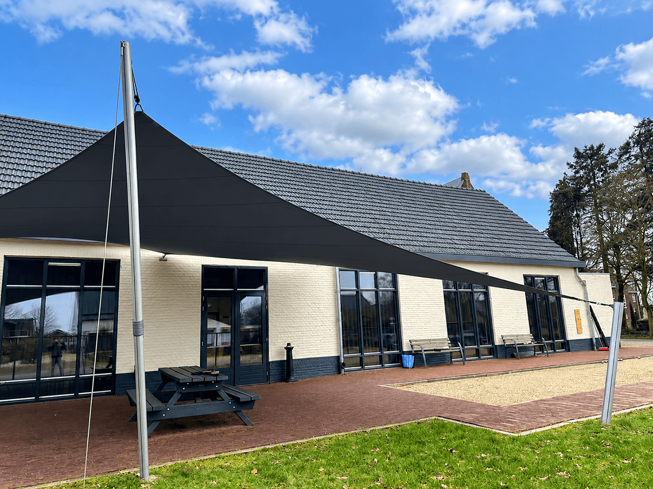 Luxe design schaduwdoek boven het terras van een moderne loftwoning met grote raampartijen.