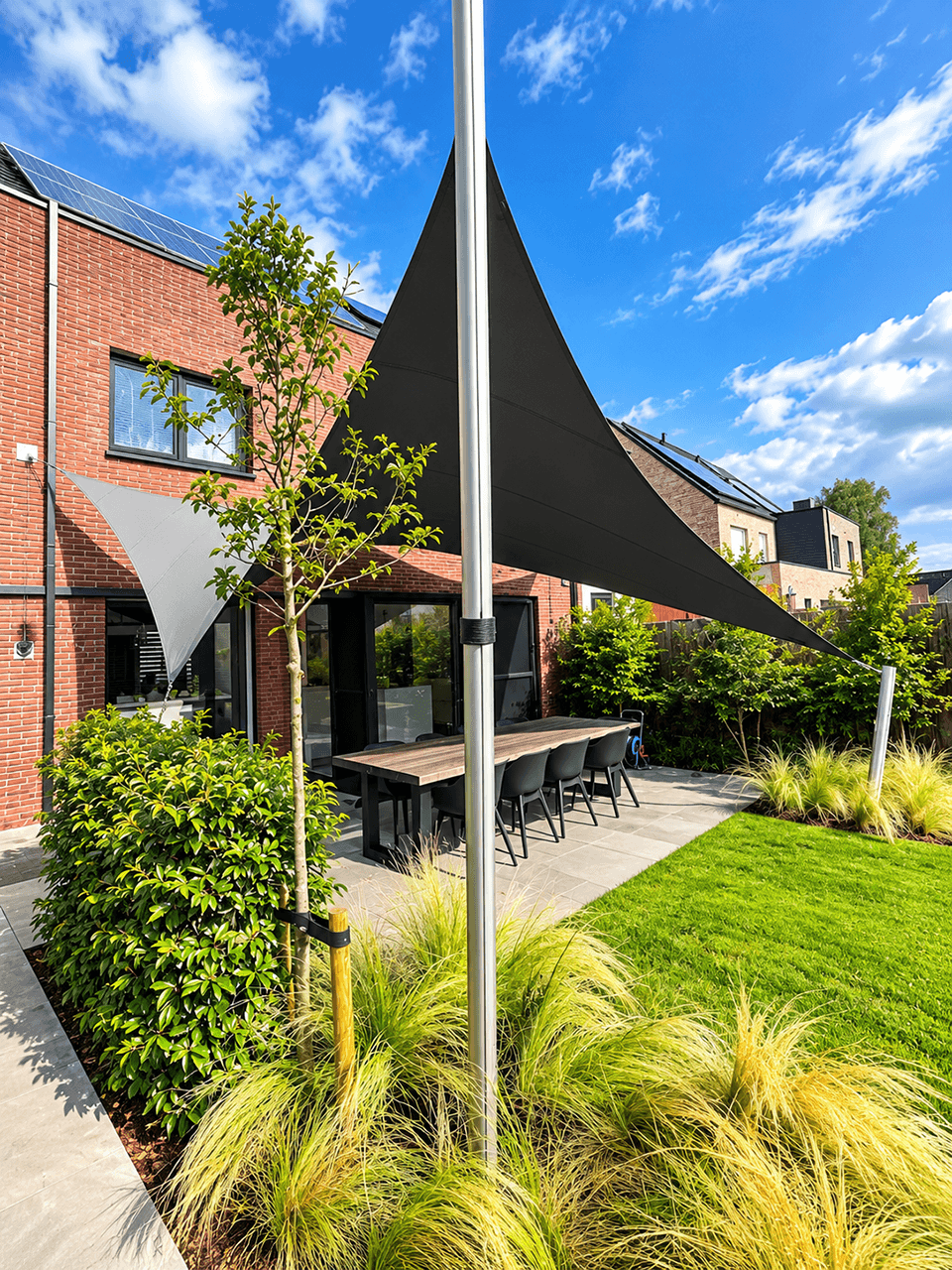 Maatwerk schaduwdoek boven een terras in de tuin van een moderne woning.