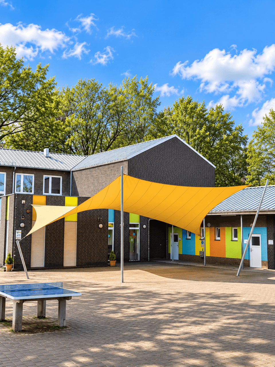 Groot maatwerk zonnedoek boven een schoolplein, gespannen tussen meerdere masten.
