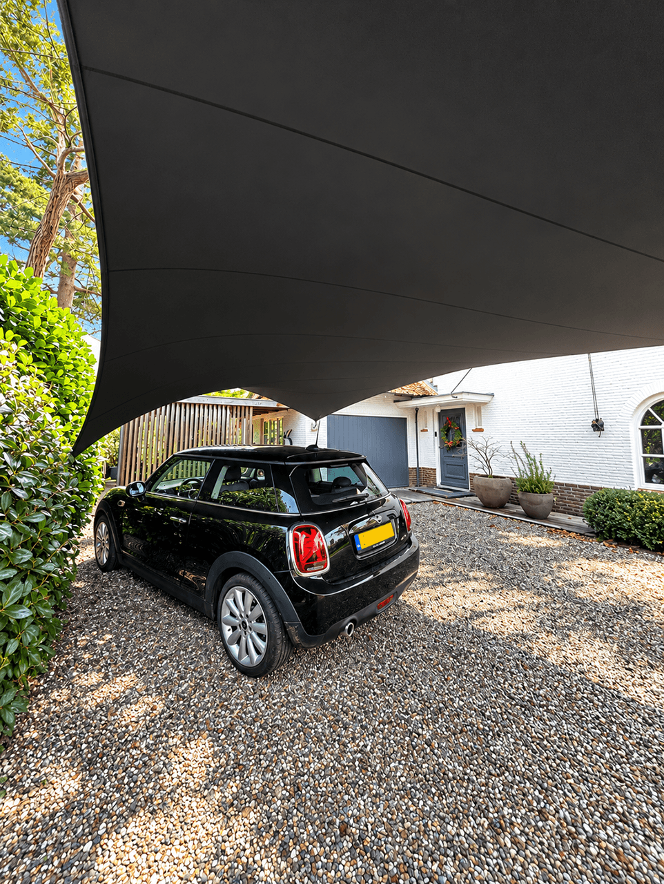 Textiele design carport boven een auto op de oprit bij een woning.