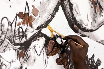 close up of Khari Turner hand-finishing a print with gold paint