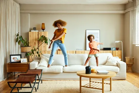 black mother and son happily dancing on the sofa