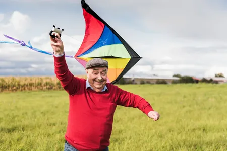 senior man happily flying kite in field