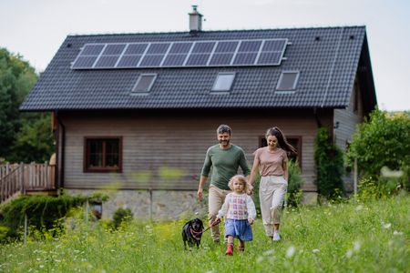 A house with solar panels, and a family walking by it