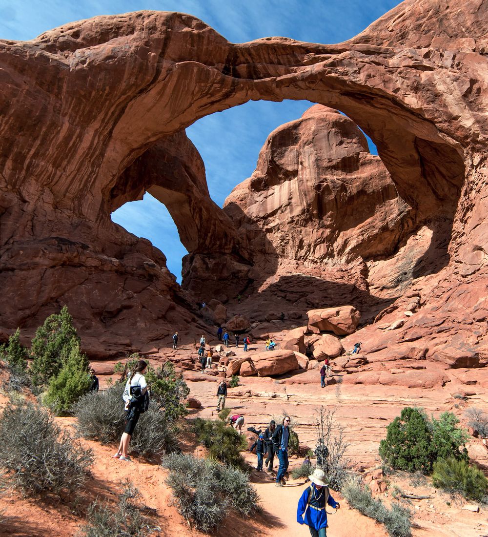Tourists walking through double arch in arches national park