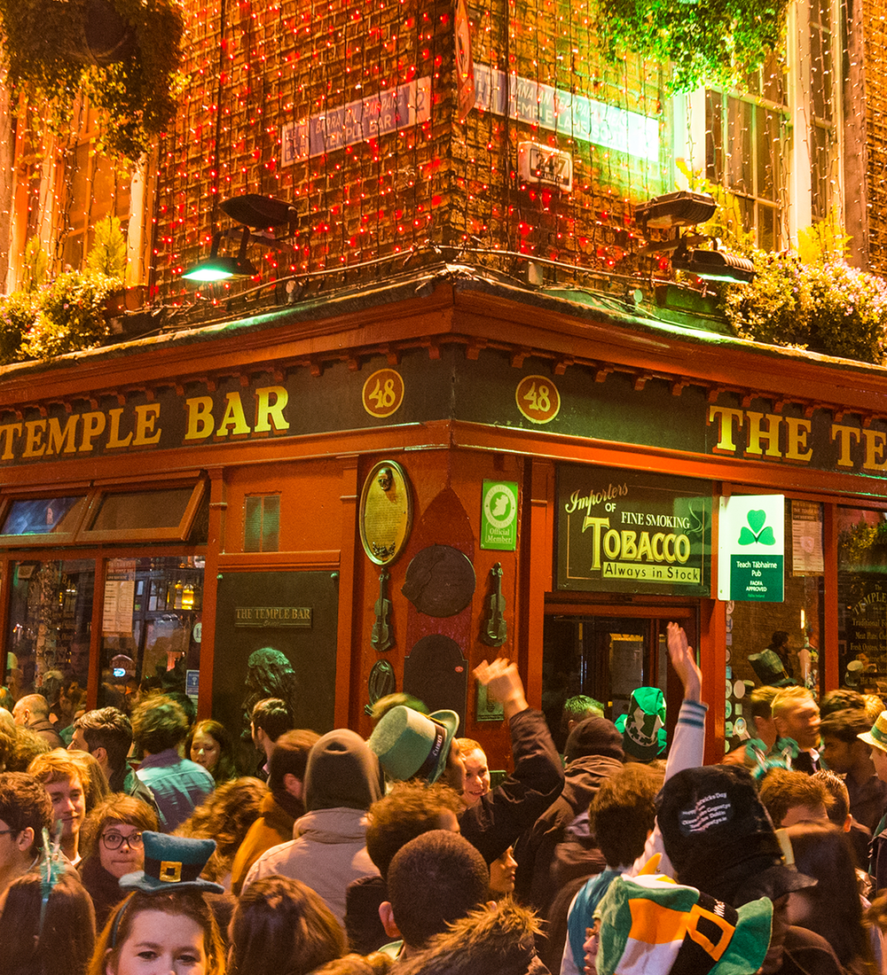 crowd of people dressed up for st patricks day in front of temple bar in dublin ireland
