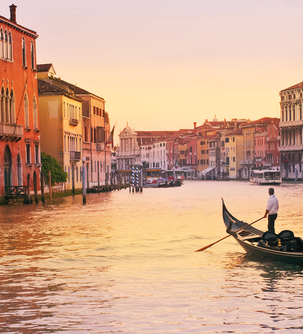 venetian gondolier riding on gondola through canal in venice italy