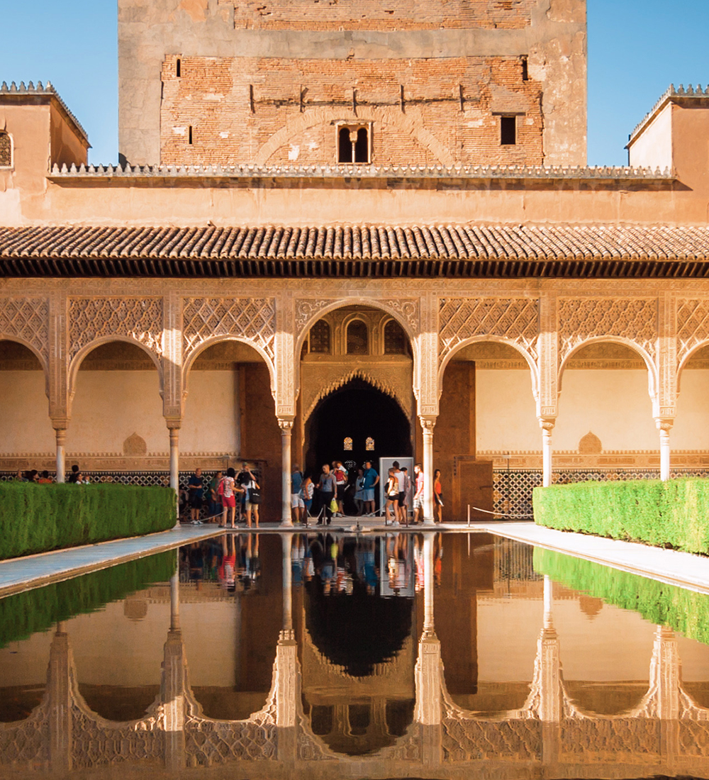 people walking around the view of alhambra palace in granada spain